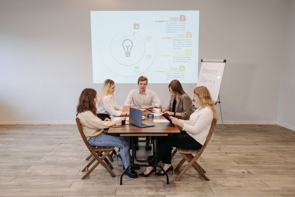Group of professionals engaging in a teamwork session with a projected presentation in an office.